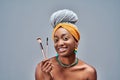 Smiling afro american woman holding makeup brushes isolated on a grey background Royalty Free Stock Photo