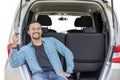 Smiling Afro man holds a new car key in car trunk Royalty Free Stock Photo