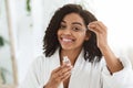 Smiling Afro Woman Applying Hydrating Face Serum On Her Beautiful Skin Royalty Free Stock Photo