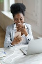 Smiling Afro woman take a break chatting with friend about weekend in social media sitting at office Royalty Free Stock Photo