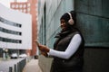 Smiling afro woman using mobile phone while standing outdoors at city street Royalty Free Stock Photo