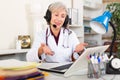 Smiling aged female doctor in headset conducting online consultation Royalty Free Stock Photo