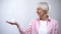 Smiling aged female holding pills, health care in old age, illness treatment Royalty Free Stock Photo