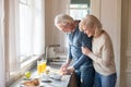 Happy aged woman embrace husband cooking healthy breakfast Royalty Free Stock Photo