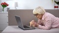 Smiling aged woman chatting on laptop with family, studying social networks Royalty Free Stock Photo