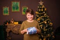 Smiling aged woman holding a gift in her hands while standing against the background of the Christmas interior and Christmas tree Royalty Free Stock Photo