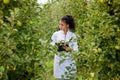 Smiling agronomist with notebook standing in apple orchard Royalty Free Stock Photo
