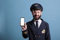 Smiling airplane pilot showing smartphone with blank white screen