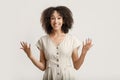 Smiling amazed shocked african american young woman looking at camera and raises hands up Royalty Free Stock Photo