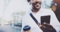 Smiling American African man in headphone walking at sunny city with take away coffee and enjoying to listen to music on Royalty Free Stock Photo