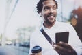 Smiling American African man in headphone walking at sunny city with take away coffee and enjoying to listen to music on Royalty Free Stock Photo