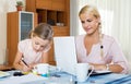 Businesswoman browsing internet at home, daughter drawing in pencil Royalty Free Stock Photo