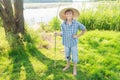 Smiling angling teenage boy with handmade green twig fishing rod in hand Royalty Free Stock Photo