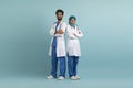 Smiling arab male and female doctors posing in uniform over blue background Royalty Free Stock Photo