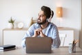 Smiling arab man in headphones listening music while working on laptop Royalty Free Stock Photo
