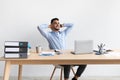 Smiling Arab man leaning back sitting at desk Royalty Free Stock Photo