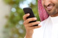 Smiling arab saudi man hand using a smart phone outdoor Royalty Free Stock Photo