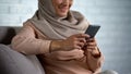 Smiling arab woman in hijab watching photos on smartphone, good memories Royalty Free Stock Photo