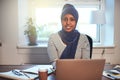 Smiling Arabic female entrepreneur working at home on a laptop Royalty Free Stock Photo