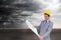 Smiling architect with hard hat looking at plans Royalty Free Stock Photo