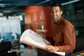 Smiling architect reading blueprints while working late in an office Royalty Free Stock Photo