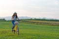 Smiling Asia woman with bicycling at the garden meadow in sunset near mountain background.