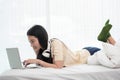 Smiling asia woman using a laptop while lying on her bed, inspiration, creativity, comfort and people concept Royalty Free Stock Photo