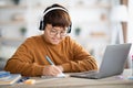 Smiling asian boy schooler having online lesson from home