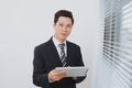 Smiling asian businesman holding digital tablet standing by the Royalty Free Stock Photo