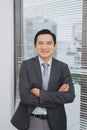 Smiling asian businesman standing by the window. Royalty Free Stock Photo