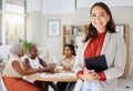 Smiling asian business woman holding a digital tablet while colleagues sit behind her in office. Ambitious and happy Royalty Free Stock Photo