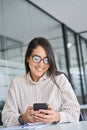 Smiling Asian business woman using mobile phone working in office. Royalty Free Stock Photo