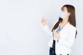 Smiling Asian business woman wearing a medical face mask and pointing finger to side blank space over grey background. Back to the Royalty Free Stock Photo