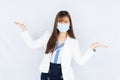 Smiling Asian business woman wearing a medical face mask and pointing hand to side blank space over grey background. Back to the Royalty Free Stock Photo
