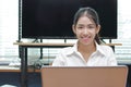 Smiling Asian business woman working with laptop in office