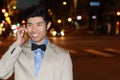 Smiling Asian businessman calling by phone on the street at night - Stock image Royalty Free Stock Photo