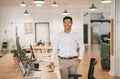 Smiling Asian businessman standing by his desk in an office Royalty Free Stock Photo