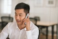 Smiling Asian businessman talking on a cellphone at work Royalty Free Stock Photo