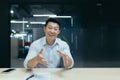 Smiling asian businessman talking on video call, looking at camera while sitting at desk in office. Gestures, discusses Royalty Free Stock Photo
