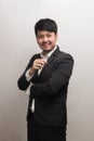 Smiling Asian businessman with white shirt and black suite holding pen, look at camera, isolate on grey background Royalty Free Stock Photo