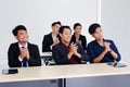 Smiling Asian businesspeople are clapping and having a seminar in the economics class in meeting room. Collegians are learning