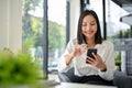 Smiling Asian businesswoman chatting with her friends on her phone while relaxing in the office Royalty Free Stock Photo