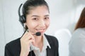 Smiling Asian businesswoman consultant wearing microphone headset of customer support phone operator at workplace. Royalty Free Stock Photo