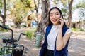 Smiling asian businesswoman hold reusable eco-friendly ecological cup and using mobile while sitting at park Royalty Free Stock Photo