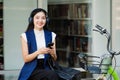 Smiling asian businesswoman hold reusable eco-friendly ecological cup and using mobile while sitting at park Royalty Free Stock Photo