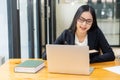 Smiling Asian businesswoman in the modern office using the laptop and looking at camera while sitting at her desk in modern office Royalty Free Stock Photo