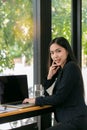 Smiling Asian businesswoman in the modern office using the laptop and looking at camera while sitting at her desk in modern office Royalty Free Stock Photo