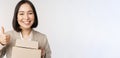 Smiling asian businesswoman, showing thumbs up and boxes with delivery goods, prepare order for client, standing over Royalty Free Stock Photo