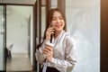 A smiling Asian businesswoman is talking on the phone in an office corridor Royalty Free Stock Photo