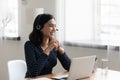 Smiling Asian businesswoman wearing headset using laptop, looking to aside Royalty Free Stock Photo